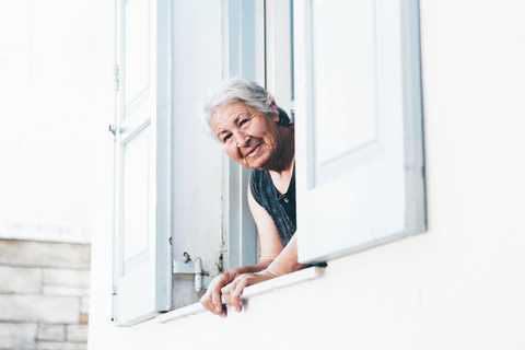Une dâme âgée souriante à son balcon